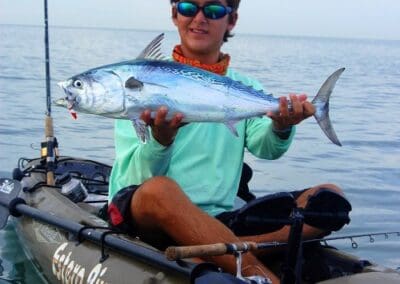 Person holding fish on kayak in ocean