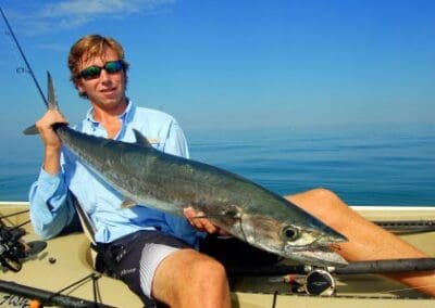 Man holding kingfish on boat in ocean