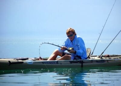 Man kayak fishing in calm ocean waters.