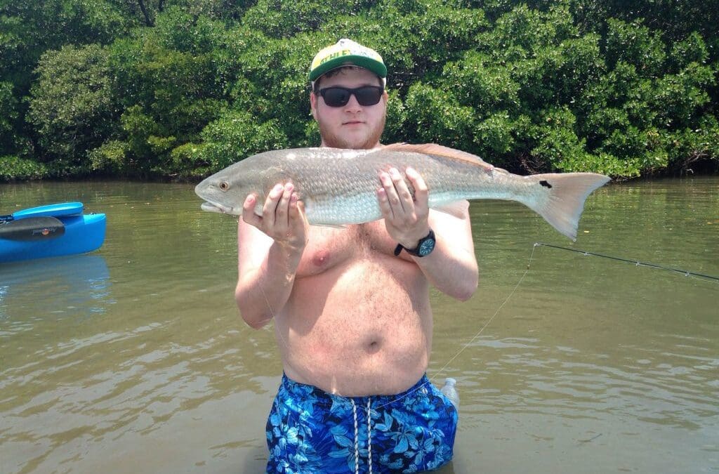 Man holding a large fish in the water.