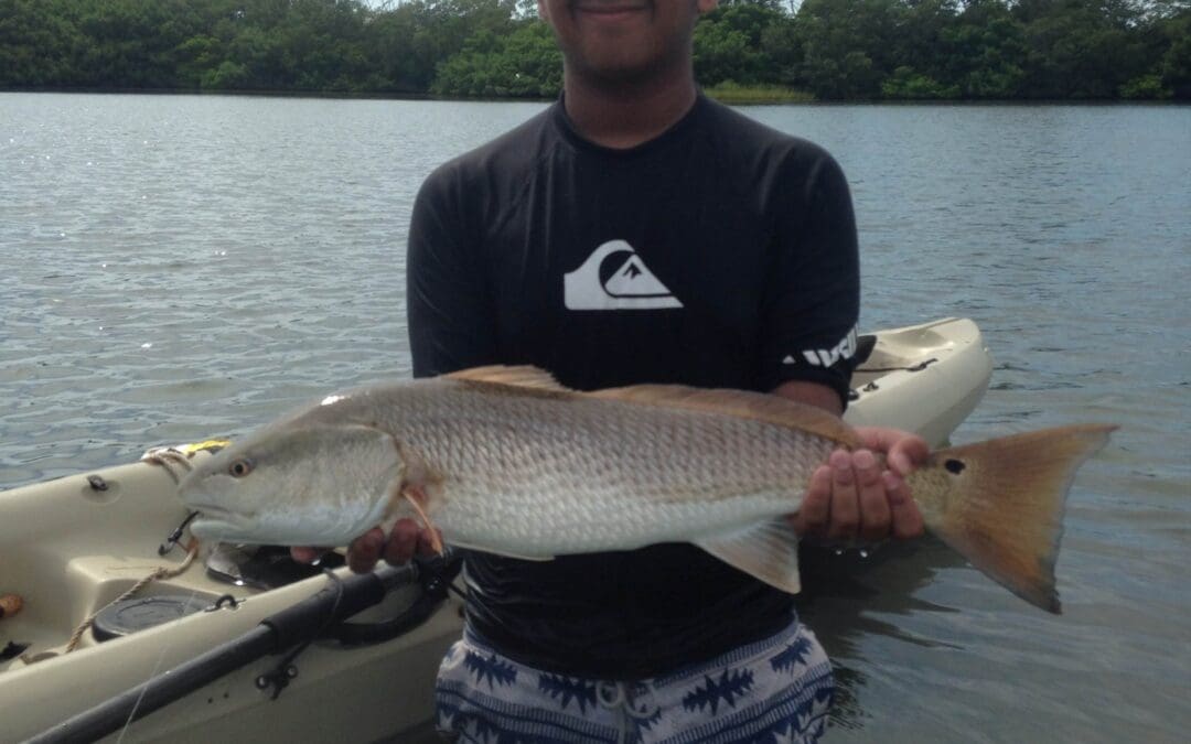 Person holding fish near kayak on lake