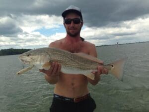 Man holding large fish by the water.