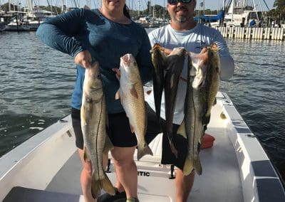 husband and wife holding fish caught on a inshore fishing charter by seein red sport fishing charters