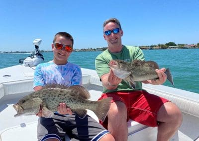 father and son holding their fish they caught on tampa bay fishing charter