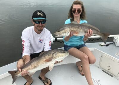 2 passengers holding their catch at the end of the inshore fishing trip